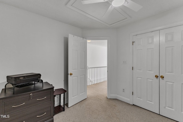 carpeted bedroom with attic access, baseboards, a ceiling fan, and a closet