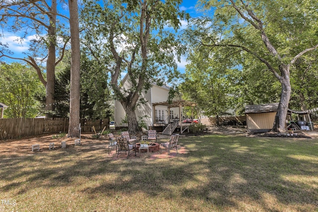 view of yard featuring a fire pit, a pergola, a shed, and an outbuilding
