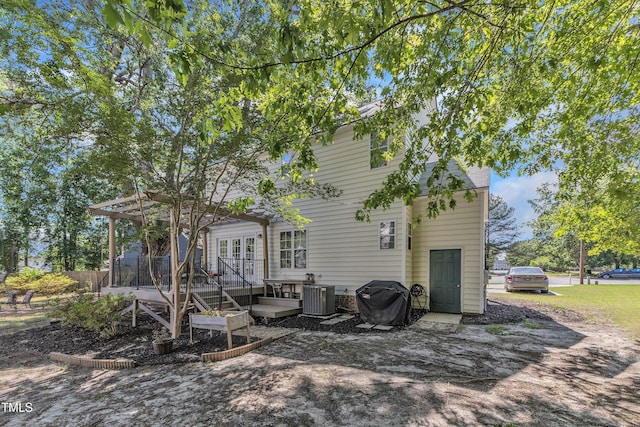 rear view of property featuring a deck, cooling unit, and a sunroom