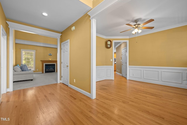 1420 Norwood Crest Ct, Raleigh, NC 27614 - unfurnished living room featuring ceiling fan, light wood-type flooring, a fireplace, a wainscoted wall, and crown molding