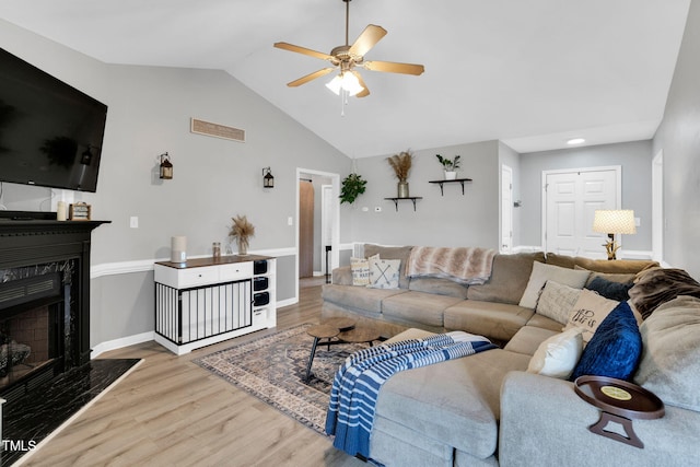 living room with ceiling fan, baseboards, wood finished floors, a high end fireplace, and vaulted ceiling