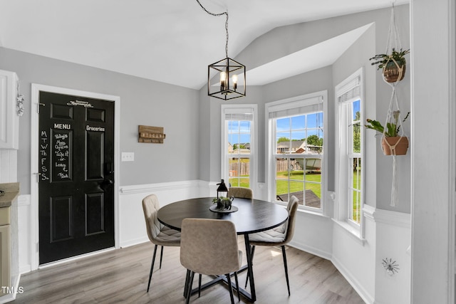 dining room featuring a healthy amount of sunlight, vaulted ceiling, and light wood-style flooring
