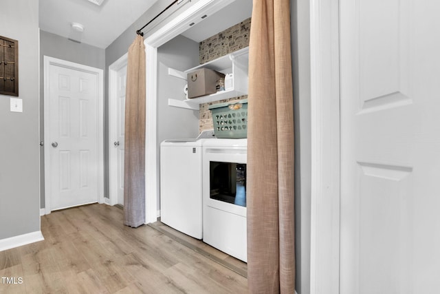 washroom with laundry area, washer and clothes dryer, light wood finished floors, and baseboards
