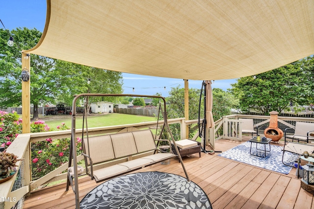 wooden deck featuring a fenced backyard, a storage unit, a yard, and outdoor lounge area