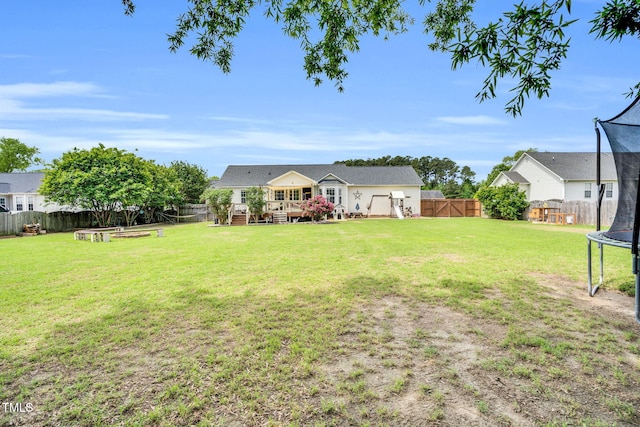 view of yard featuring a fenced backyard, a gate, a trampoline, and a deck