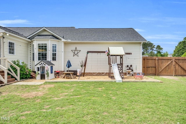 rear view of property featuring a lawn, a gate, roof with shingles, and fence