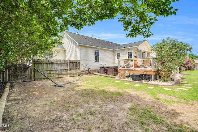 back of property with fence, a wooden deck, a gate, a lawn, and a hot tub