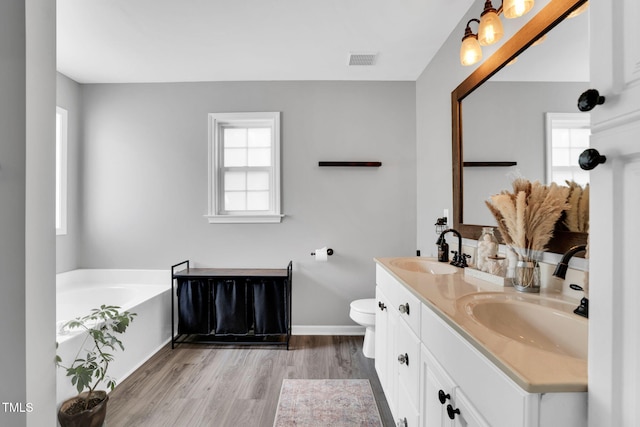full bath featuring a sink, plenty of natural light, wood finished floors, and visible vents