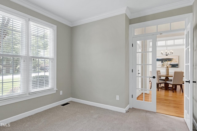 spare room with baseboards, a chandelier, ornamental molding, and visible vents
