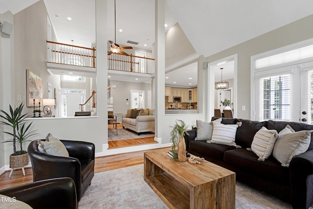 living area with a ceiling fan, baseboards, wood finished floors, a towering ceiling, and stairway