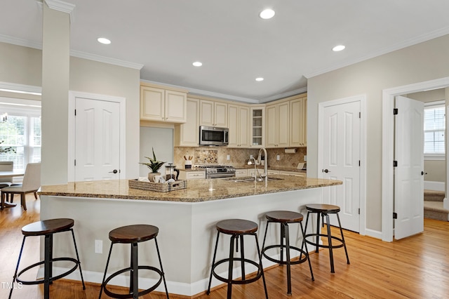 kitchen featuring a sink, light wood finished floors, appliances with stainless steel finishes, and cream cabinetry