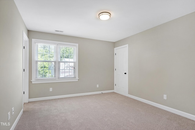 empty room featuring visible vents, baseboards, and light carpet