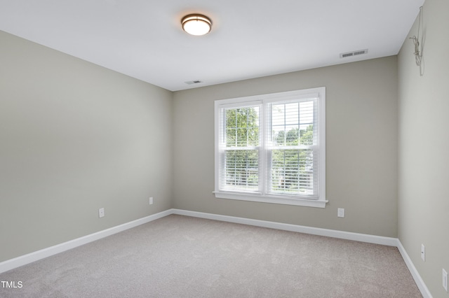 unfurnished room with baseboards, visible vents, and light carpet
