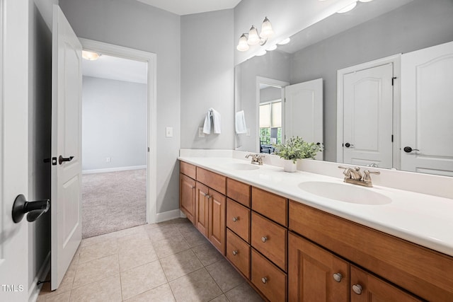 bathroom with a sink, baseboards, tile patterned floors, and double vanity
