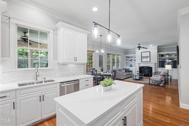 kitchen with ceiling fan, dishwasher, a sink, a glass covered fireplace, and ornamental molding