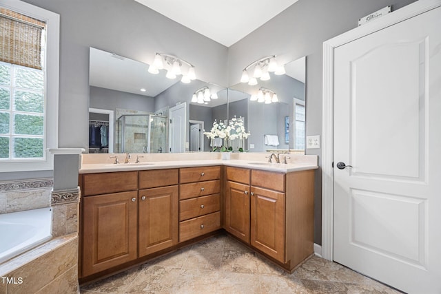 bathroom with double vanity, a sink, a garden tub, and a stall shower