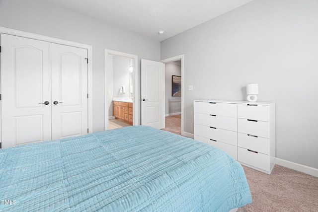 bedroom with baseboards, a closet, connected bathroom, and light colored carpet