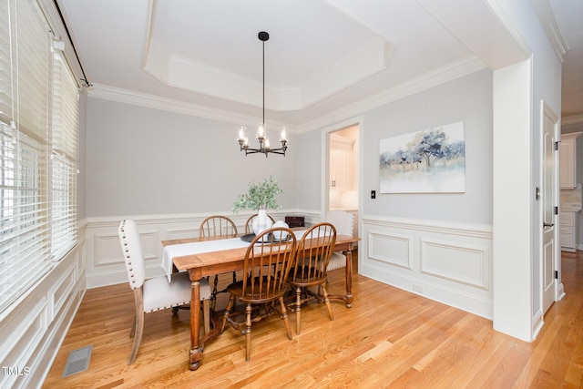 2728 Cameron Pond Dr, Cary, NC 27519 - dining space featuring a chandelier, light wood-type flooring, a tray ceiling, a wainscoted wall, and a decorative wall