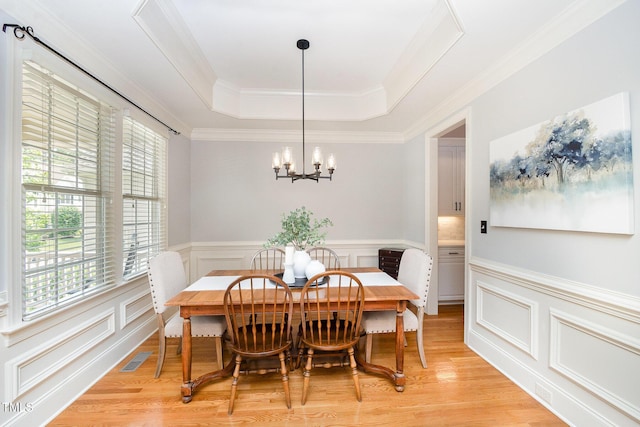 2728 Cameron Pond Dr, Cary, NC 27519 - dining space with a chandelier, a raised ceiling, wainscoting, a decorative wall, and crown molding