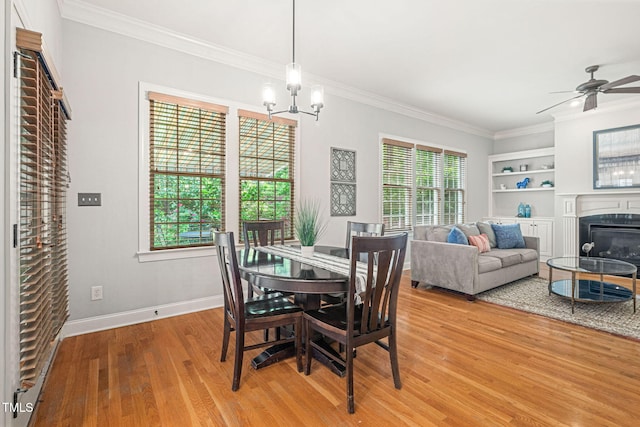 2728 Cameron Pond Dr, Cary, NC 27519 - dining area with a glass covered fireplace, ornamental molding, light wood-style floors, a chandelier, and baseboards