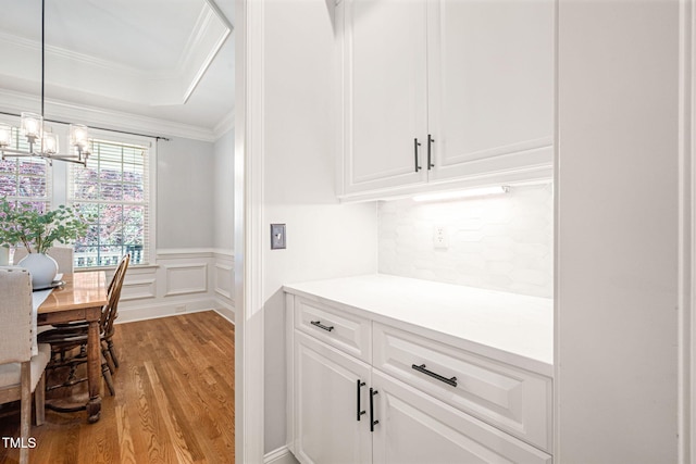 2728 Cameron Pond Dr, Cary, NC 27519 - kitchen featuring wood finished floors, crown molding, white cabinets, a chandelier, and wainscoting