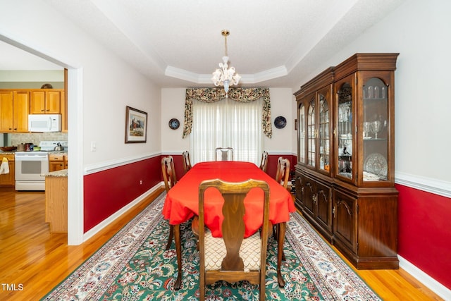 437 New Parkside Dr, Chapel Hill, NC 27516 - dining room featuring ornamental molding, baseboards, a tray ceiling, light wood-style flooring, and a notable chandelier
