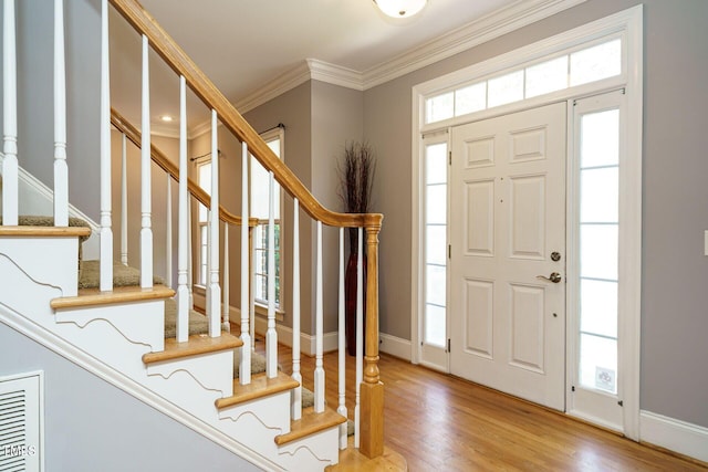 foyer featuring baseboards, ornamental molding, wood finished floors, and stairway