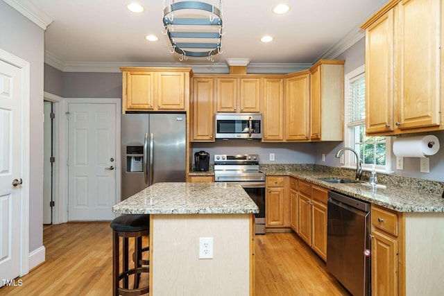 kitchen featuring a kitchen island, appliances with stainless steel finishes, a sink, light wood finished floors, and ornamental molding