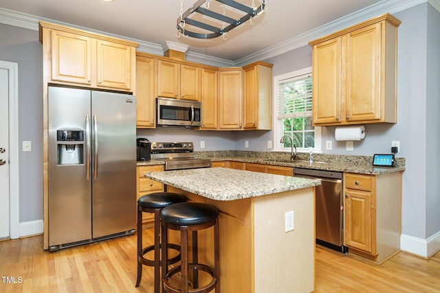 kitchen with a kitchen island, crown molding, light wood-type flooring, a sink, and stainless steel appliances