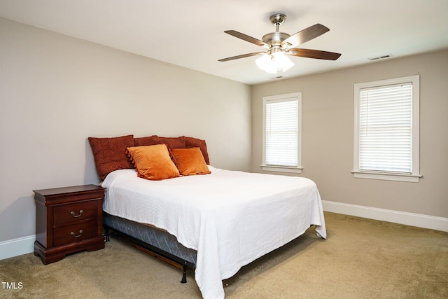 bedroom with baseboards, a ceiling fan, light colored carpet, and visible vents