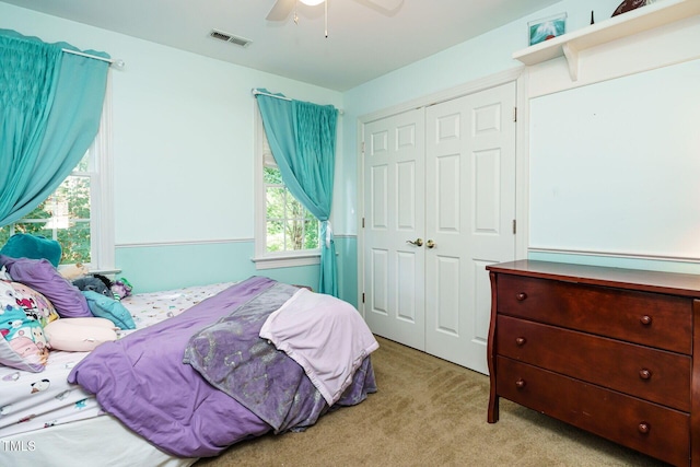 carpeted bedroom with visible vents, a ceiling fan, and a closet