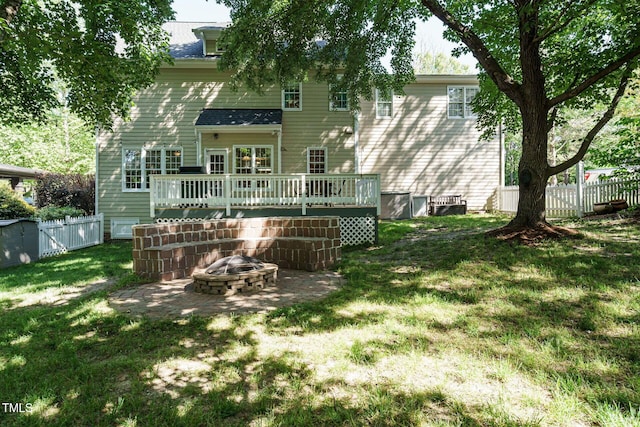 back of house with a yard, fence, a wooden deck, and an outdoor fire pit