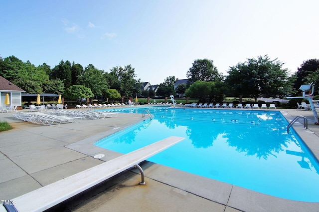 community pool featuring a diving board and a patio area