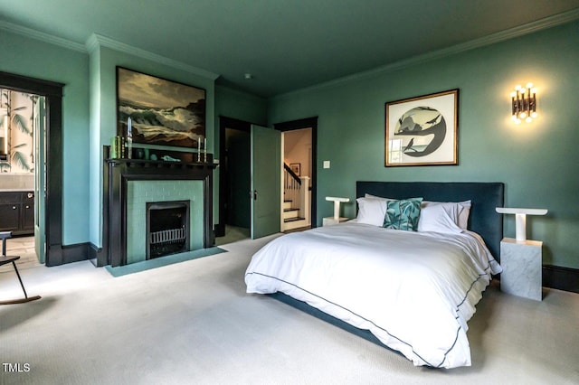 carpeted bedroom featuring baseboards, ornamental molding, ensuite bath, and a fireplace with flush hearth