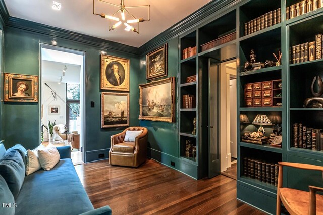 living area featuring a chandelier, wood finished floors, baseboards, and ornamental molding
