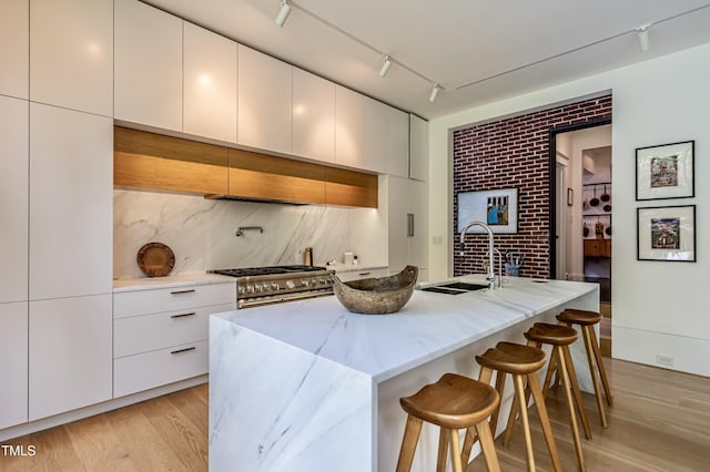 kitchen featuring a sink, a breakfast bar, modern cabinets, and high end range