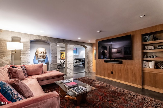 living area with recessed lighting, built in shelves, ornate columns, arched walkways, and concrete flooring