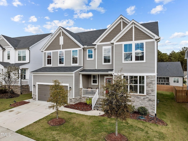 craftsman-style house with a garage, a front lawn, covered porch, stone siding, and driveway