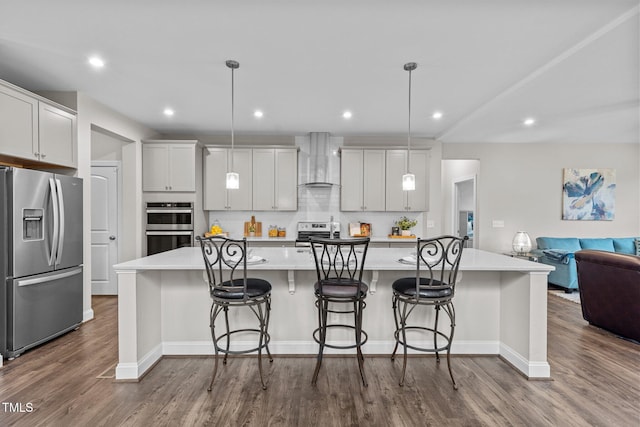 kitchen with wall chimney range hood, dark wood finished floors, light countertops, open floor plan, and stainless steel appliances