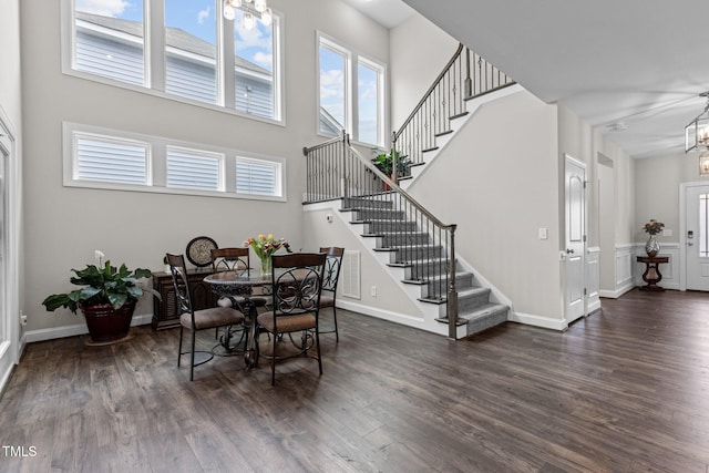 dining area featuring stairs, baseboards, a notable chandelier, and dark wood-type flooring