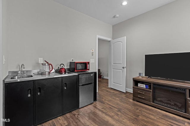 interior space featuring freestanding refrigerator, baseboards, dark wood finished floors, and a sink