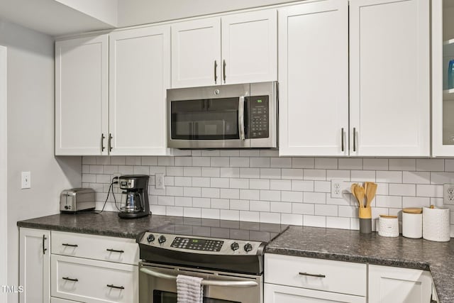 200 S Dawson St Unit 114, Raleigh, NC 27601 - kitchen featuring appliances with stainless steel finishes, white cabinetry, decorative backsplash, and dark stone countertops
