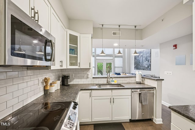 200 S Dawson St Unit 114, Raleigh, NC 27601 - kitchen with appliances with stainless steel finishes, dark wood-style floors, backsplash, white cabinets, and a peninsula