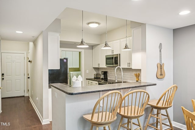 200 S Dawson St Unit 114, Raleigh, NC 27601 - kitchen with stainless steel microwave, freestanding refrigerator, dark countertops, tasteful backsplash, and white cabinetry