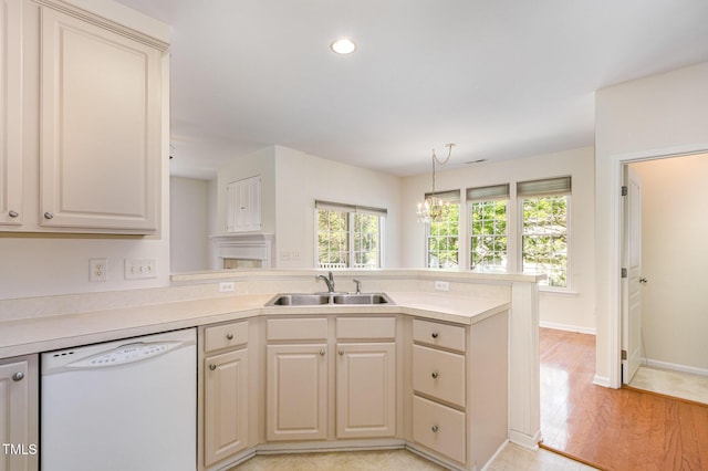 kitchen featuring white dishwasher, a sink, light wood-style floors, light countertops, and a peninsula