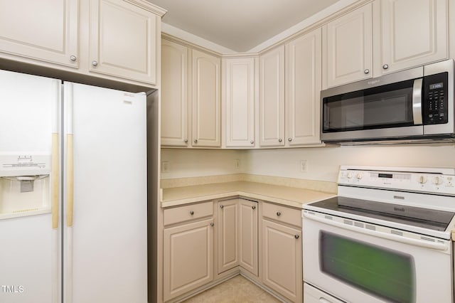 kitchen featuring light countertops, white appliances, light tile patterned flooring, and cream cabinetry