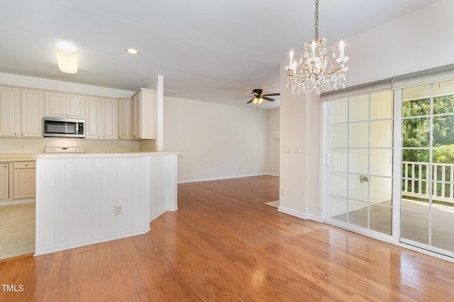 kitchen with light countertops, stainless steel microwave, ceiling fan with notable chandelier, light wood-style floors, and cream cabinetry