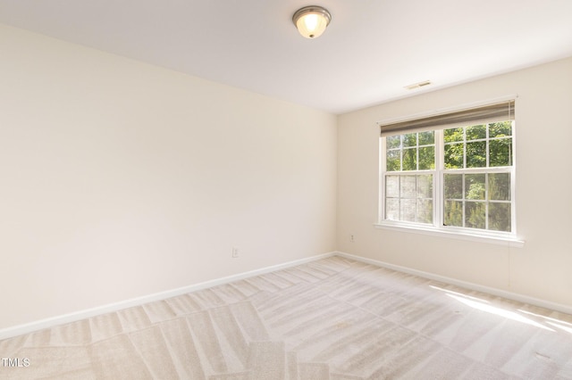 empty room featuring baseboards, visible vents, and light carpet