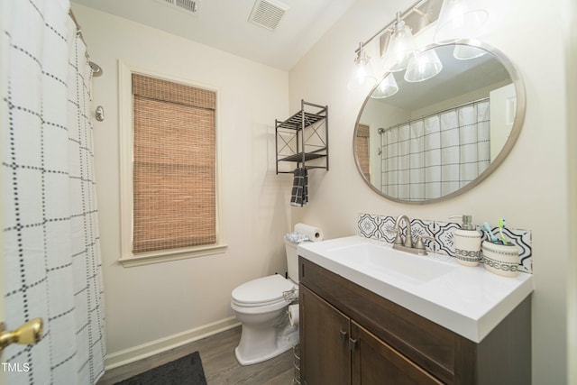 full bathroom featuring visible vents, vanity, wood finished floors, toilet, and baseboards