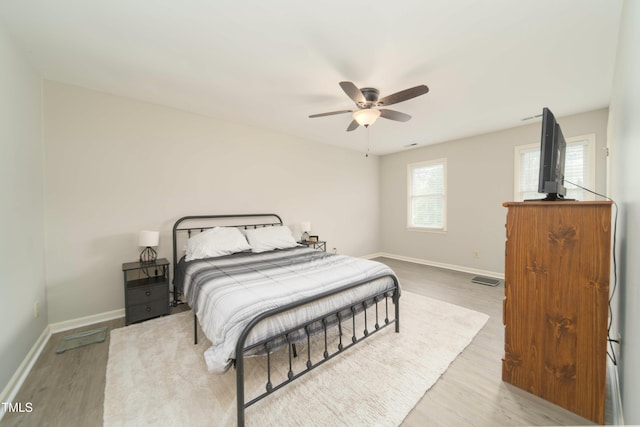 bedroom with baseboards, a ceiling fan, wood finished floors, and visible vents
